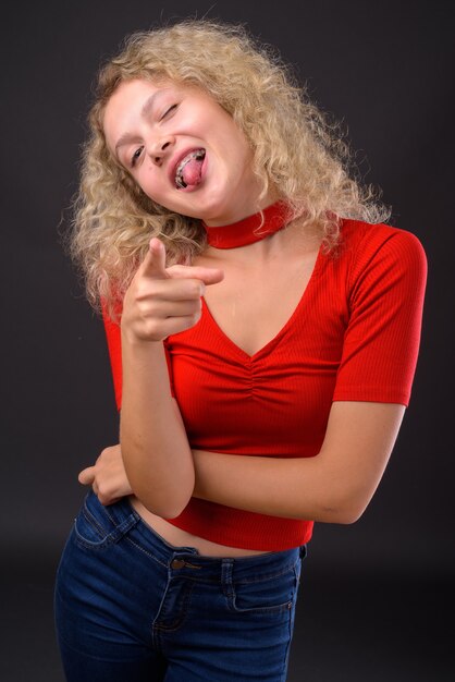 Young beautiful woman with blond curly hair against gray