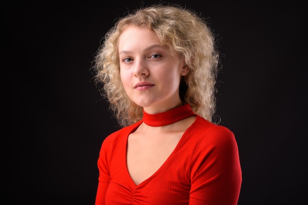 Young beautiful woman with blond curly hair against gray