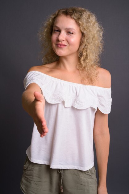 Photo young beautiful woman with blond curly hair against gray