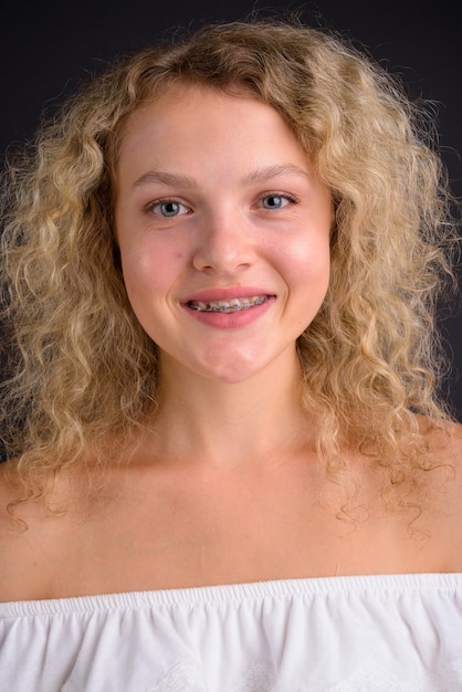 Young beautiful woman with blond curly hair against gray