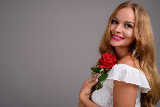 Giovane bella donna con capelli biondi su sfondo grigio