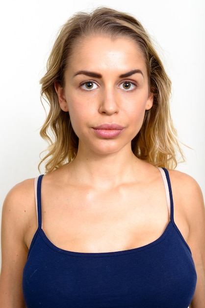 young beautiful woman with blonde wavy hair against white wall