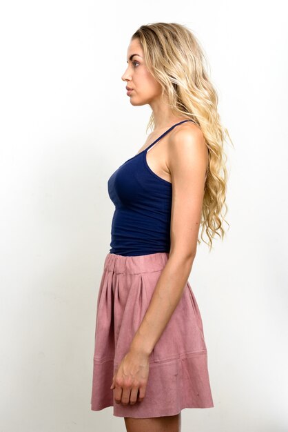 young beautiful woman with blonde wavy hair against white wall