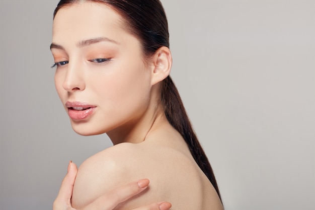 Young beautiful woman with blue eyes and full lips holds a hand on his shoulder. 