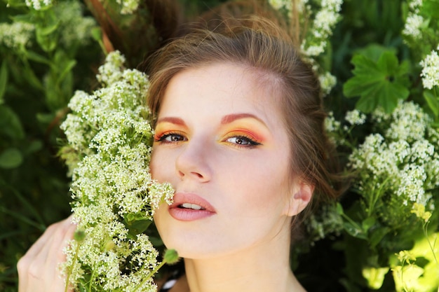 Foto giovane bella donna con trucco luminoso e fiori bianchi