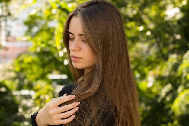 Giovane bella donna con capelli lunghi castani in camicetta nera e collana d'argento