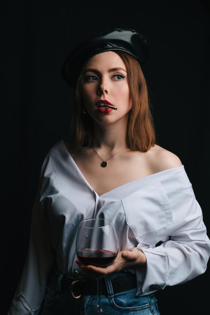 A young beautiful woman with dark hair and a beret on her head with a glass of wine and a cigarette A closeup portrait Parisian style