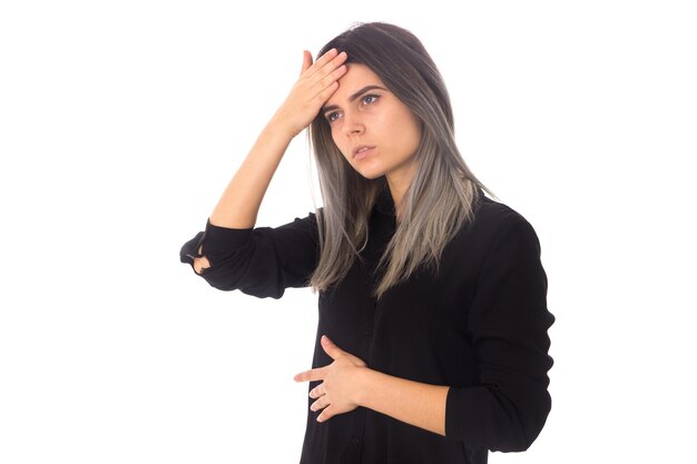 Young beautiful woman with dark hair  in black shirt having a headache on white background in studio