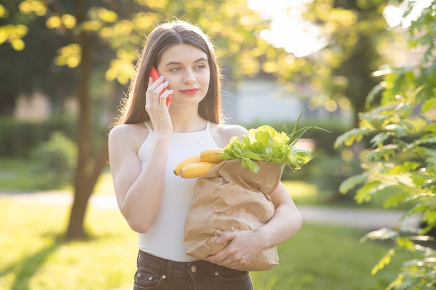 食料品の公園でフェイスマスクを持つ若い美しい女性