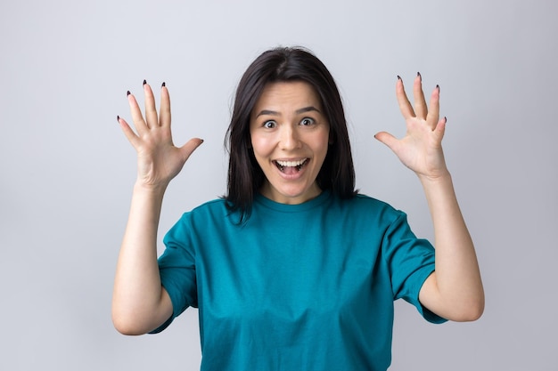 Young beautiful woman with facial expression of surprise standing over gray background