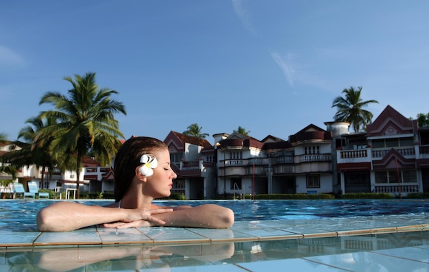 Young beautiful woman with flower in swimming pool