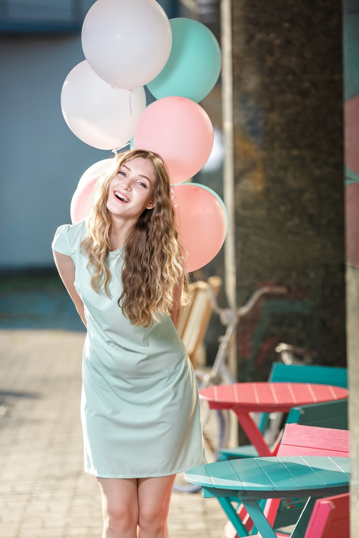 Young beautiful woman with flying multicolored balloons in the city