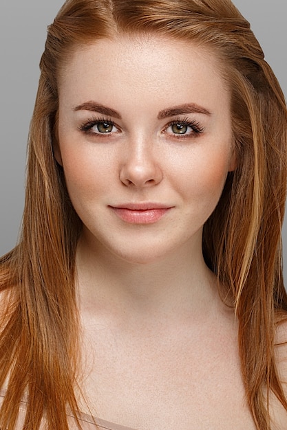 young beautiful woman with freckles portrait studio hipster posing. On gray background