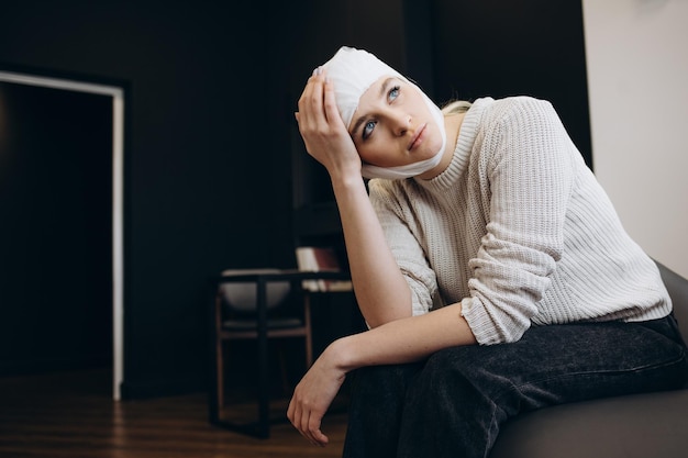 Young beautiful woman with a gauze bandage on her head and chest on black background