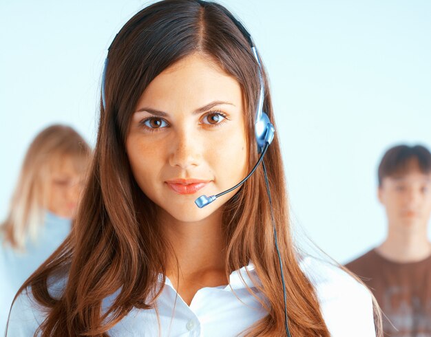 Young beautiful woman with headset with some people at the background
