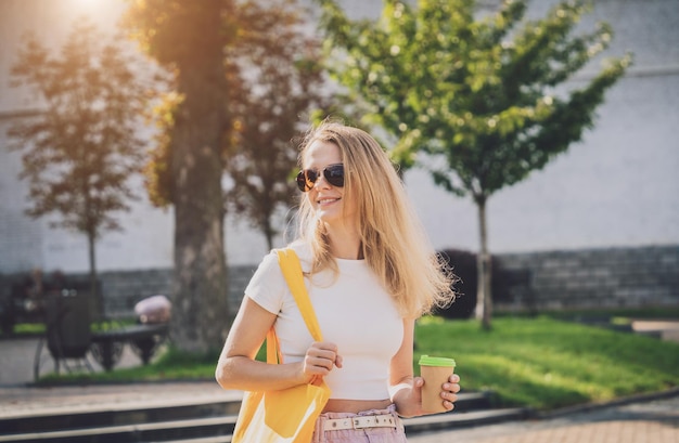 Young beautiful woman with linen eco bag on city\
background