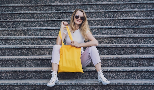 Young beautiful woman with linen eco bag on stairs background