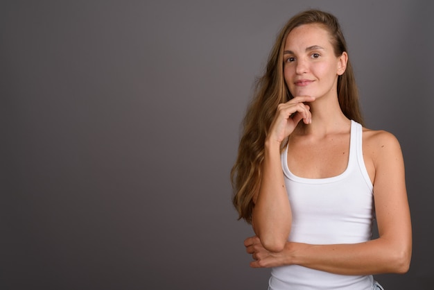 Young beautiful woman with long blond hair against gray background