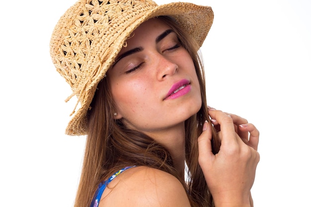 Young beautiful woman with long brown hair in blue shirt with cute hat closing eyes in studio