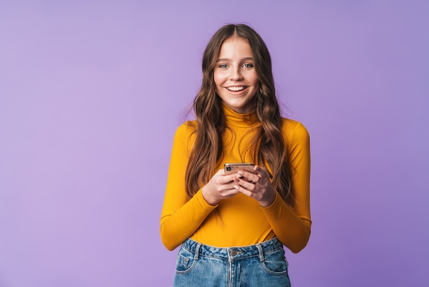 young beautiful woman with long brown hair smiling and holding cellphone isolated