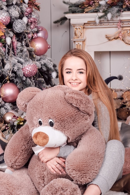 Young beautiful woman with long flowing hair smiling holding a big teddy bear