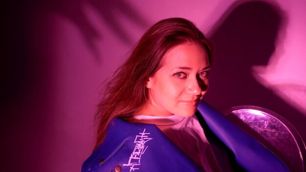 Young beautiful woman with long hair and green eyes dressed in a stylish leather jacket shot in pink neon light person