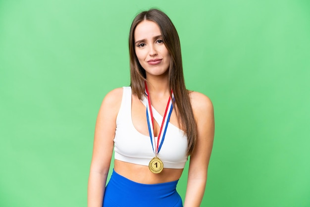 Young beautiful woman with medals over isolated chroma key background with sad expression