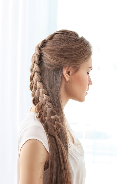 Young beautiful woman with nice braid hairstyle on light
