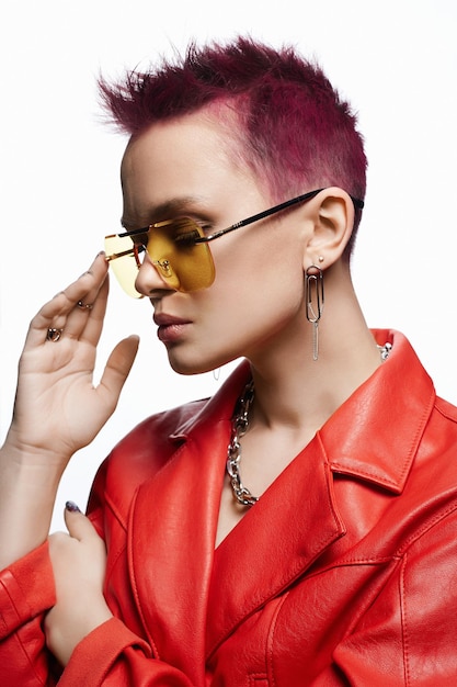 Young beautiful woman with painted short hair and a chain necklace in yellow glasses