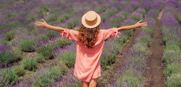 Young beautiful woman with pink dress and hat enjoying the beauty freedom and fragrance of a filed of lavender