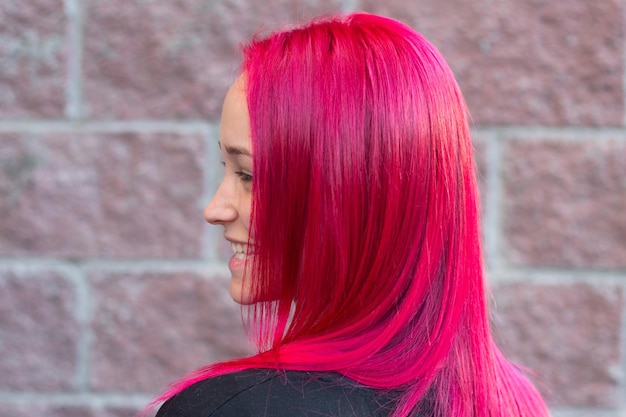 Photo young beautiful woman with pink hair on brick wall background