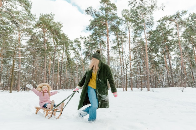겨울 공원에서 밖에서 놀고 있는 어린 소녀와 함께 아름다운 젊은 여성