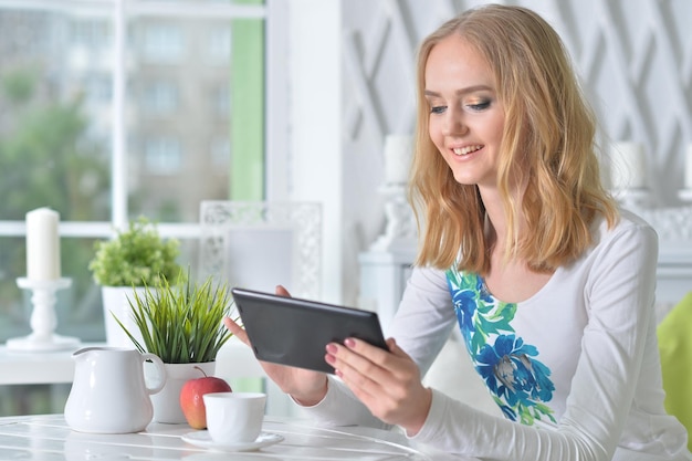 Young beautiful woman with tablet sitting at table