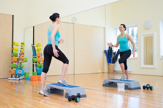 Young beautiful woman working out with stepper in gym