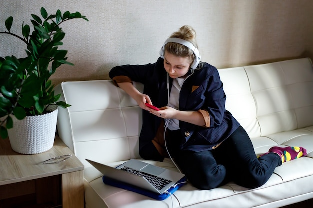 젊은 아름다운 여성은 프리랜서로 노트북을 사용하여 집에서 컴퓨터 작업을 합니다.