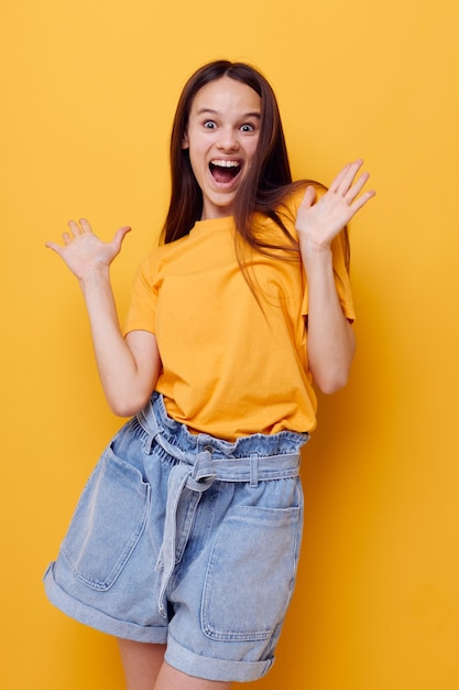 黄色のTシャツの感情の夏のスタイルの孤立した背景の若い美しい女性。高品質の写真