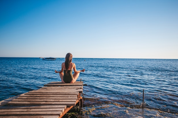 Giovane bella donna sullo yoga sulla spiaggia