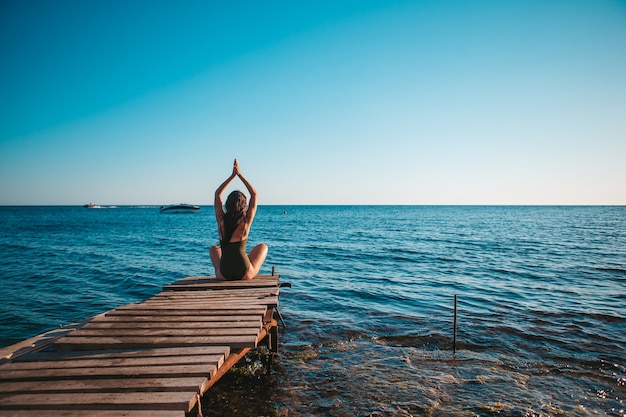 Giovane bella donna sullo yoga sulla spiaggia