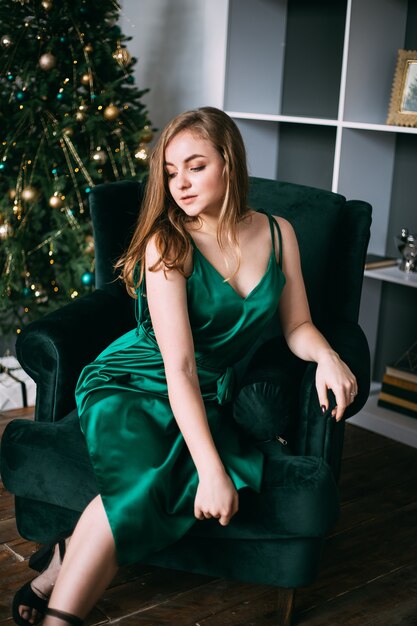 Young beautiful women in evening green dresses near decorated christmas tree