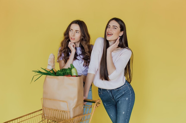 Young beautiful women holding take away paper bag from delivery over yellow background