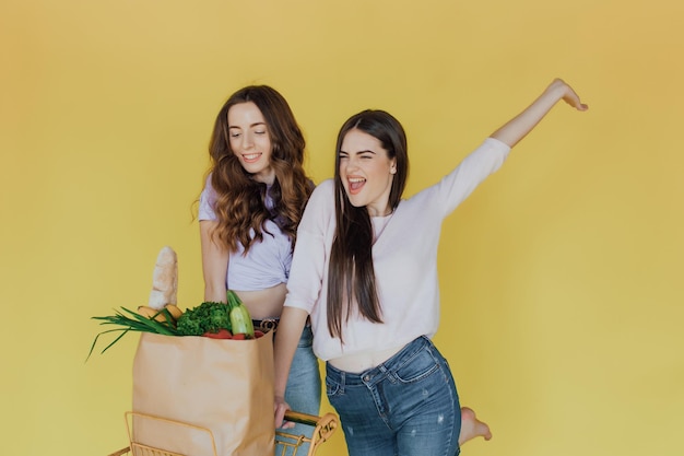 Young beautiful women holding take away paper bag from delivery over yellow background