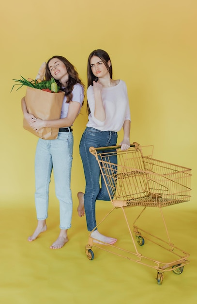 Young beautiful women holding take away paper bag from delivery over yellow background