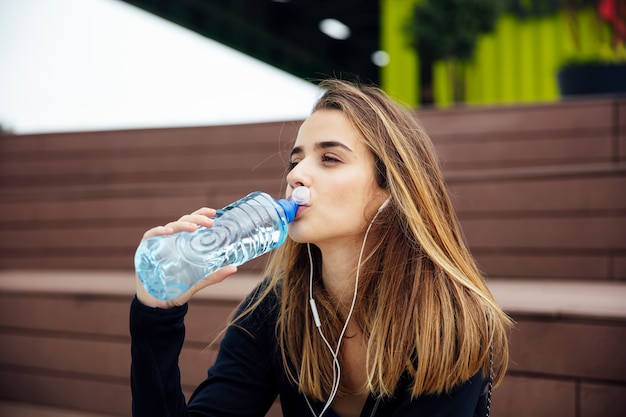 運動をした後休んで水を飲む若い美しい女性