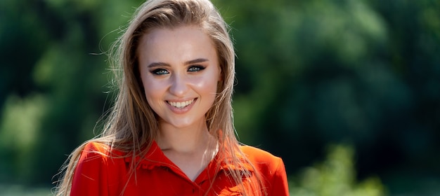 Young beauty smiling with perfect smile and white teeth in a park and looking at camera