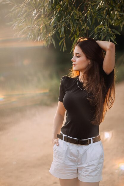 Photo a young beauty walks under the rays of the summer sun in the meadows