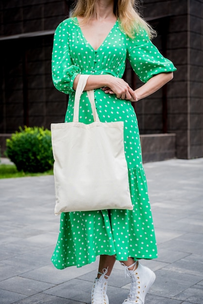 Молодая красивая женщина с льняной эко-сумкой на фоне города