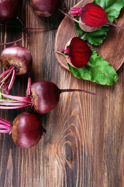 Young beets with leaves on wooden table close up