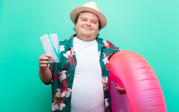 Young big size man with a inflatable donut on flat wall