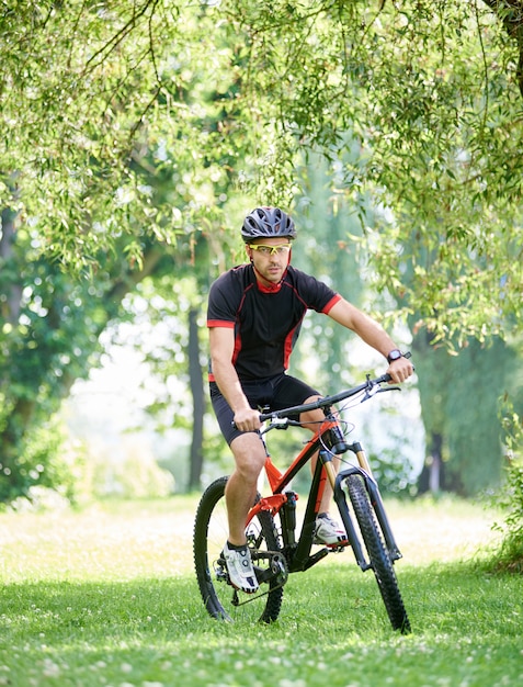 Young biker with a black bike in the park