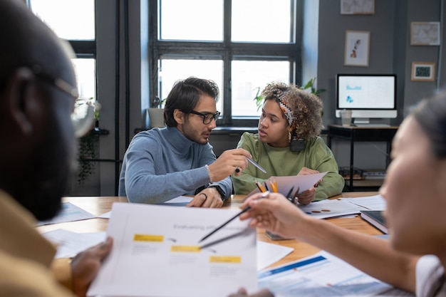 Young biracial businesswoman listening to explanations of male colleague